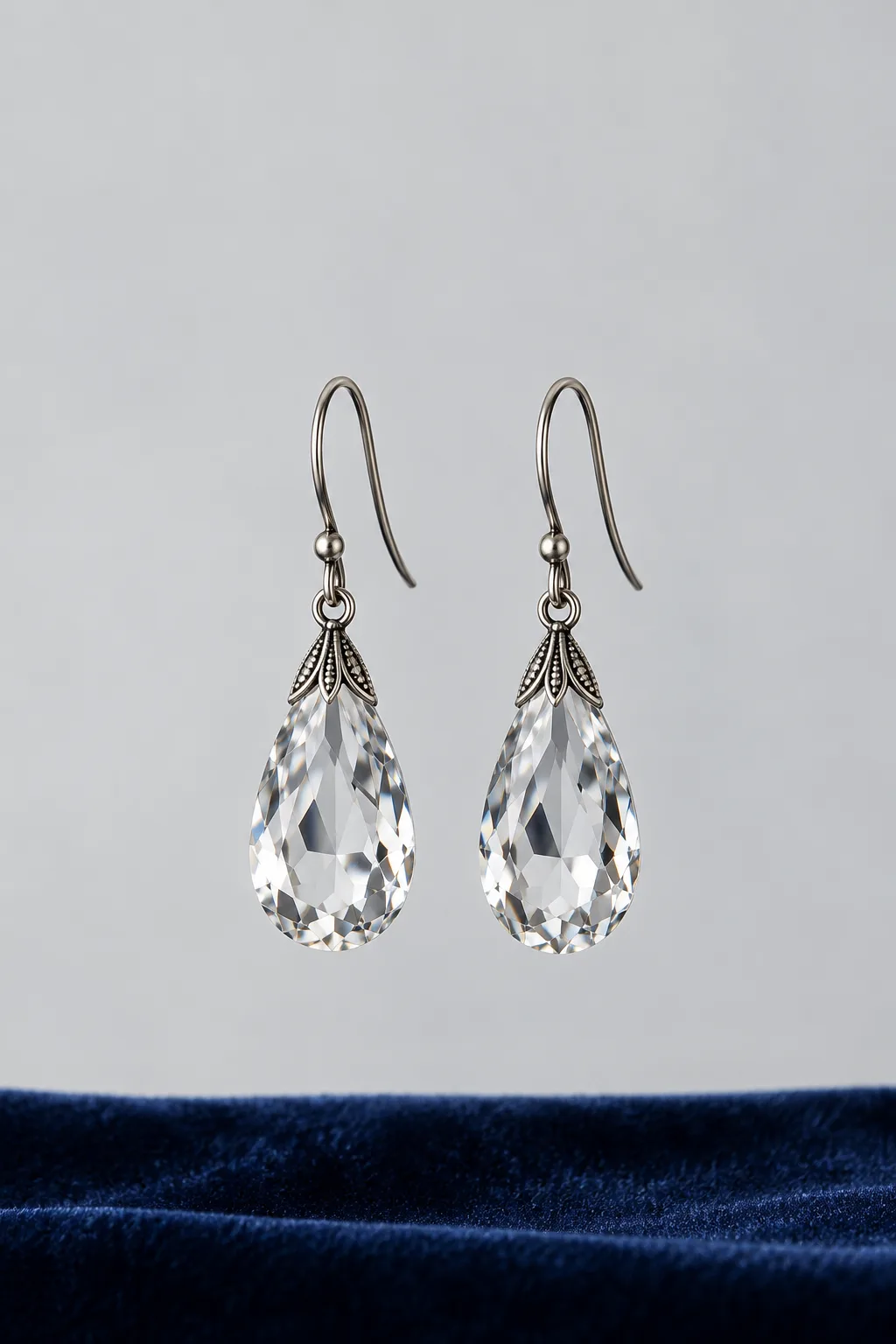 A pair of faceted crystal teardrop earrings hanging in soft light