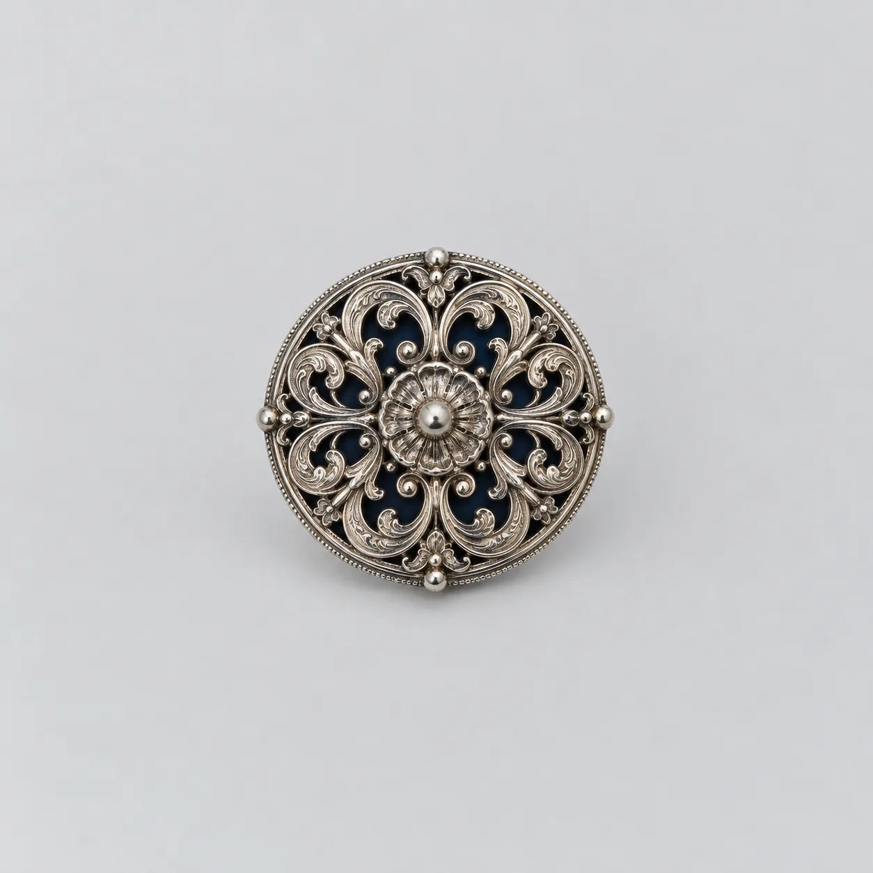 A small round silver filigree medallion on pale grey