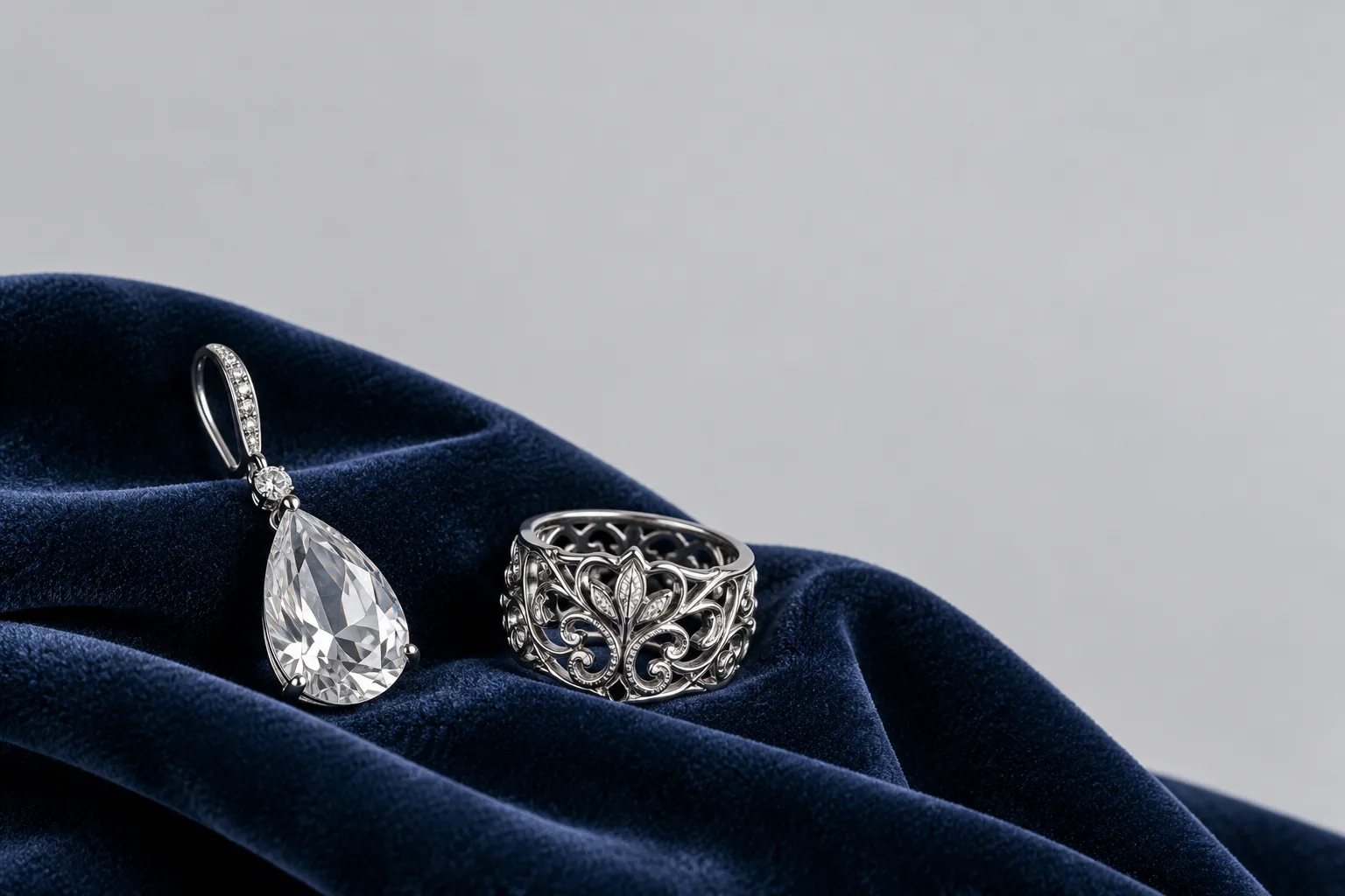 A crystal teardrop earring and a silver filigree ring on navy velvet